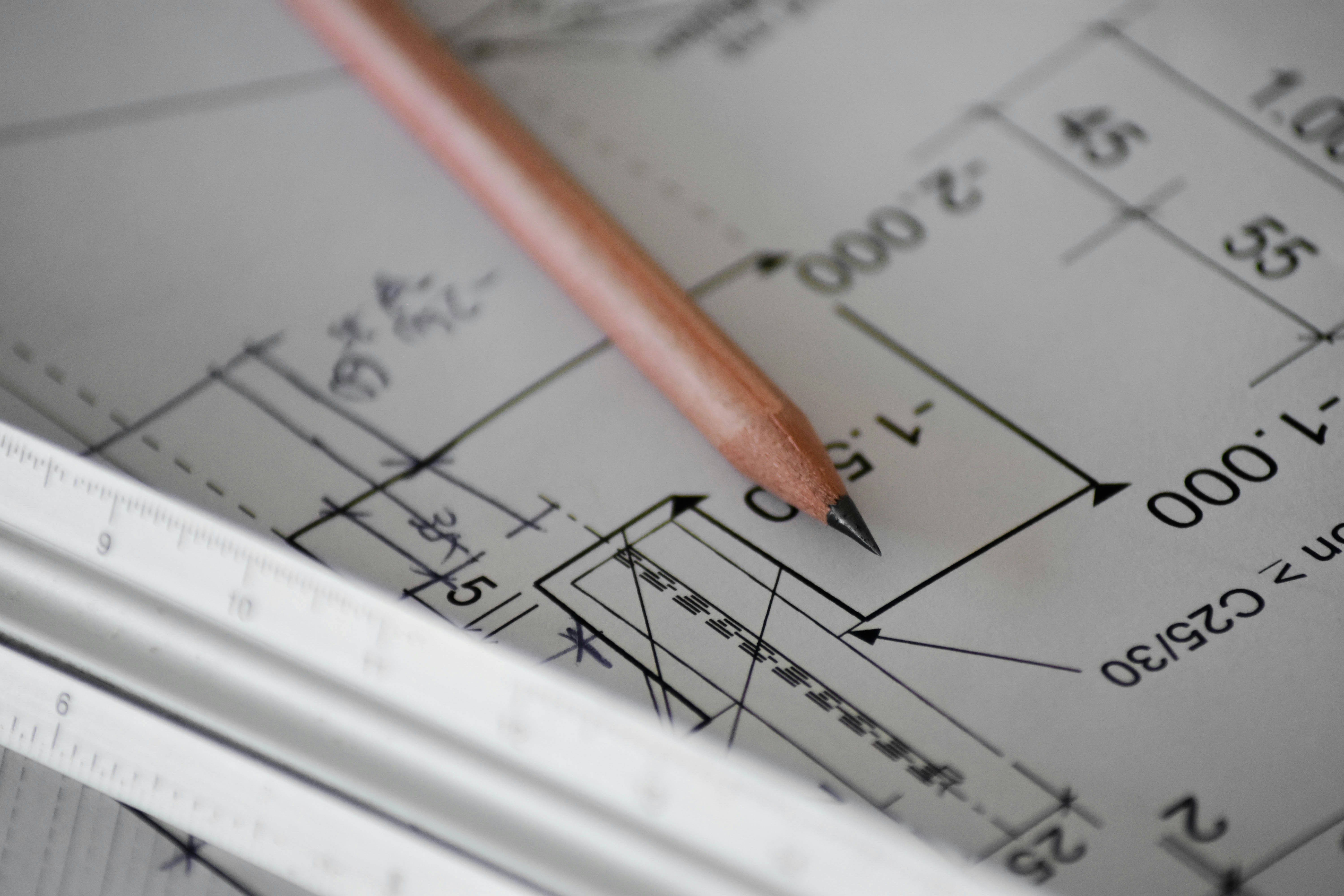 A pencil resting on a dimensioned technical drawing